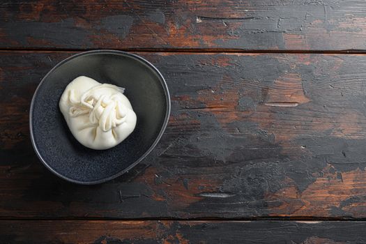 Creamy Italian Burrata Cheese in black plate over old wooden table< space for text horizontal.