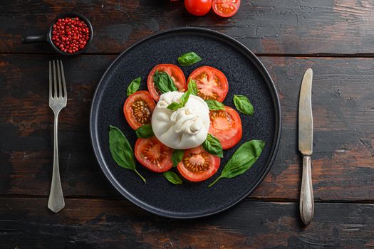 traditional italian burrata cheese Salad,olive oil, fork in plate old rustic wood planks background. Flat lay.