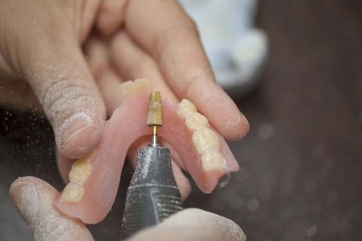 Close Dental technician make denture prothesis in dental laboratory, close up