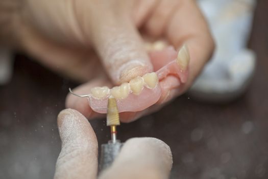 Dental technician make denture prothesis in dental laboratory, close up