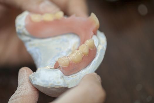 Dental technician make dental denture prothesis in dental laboratory, close up