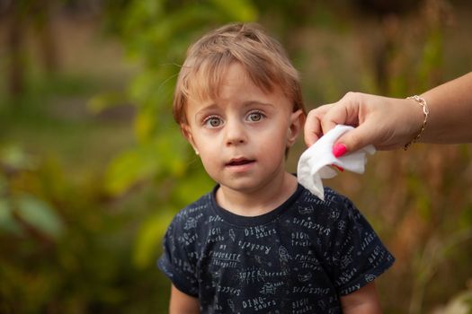 Hygiene - mom wiping the baby face skin with wet wipes. Cleaning wipe, pure, clean, outdoor