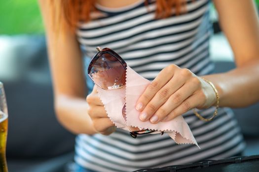 wiping sun glasses - Woman hands cleaning her sunglasses with micro fiber cloth wipe, wipping sunglasses