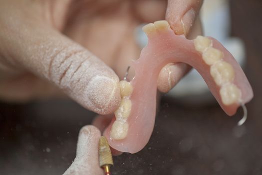 Dental technician work on denture prothesis in dental laboratory, close up