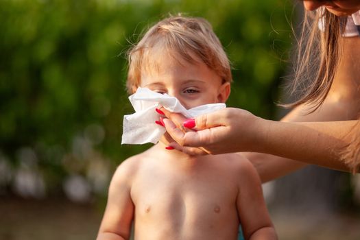 Hygiene - mom wiping the baby nose and face with wet wipes. Cleaning wipe, pure, clean, outdoor