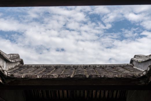 Blue sky above tiled roof of Tulou at Unesco heritage site near Xiamen