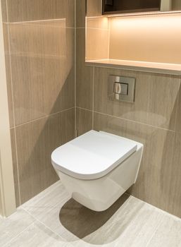 Modern toilet or WC in clean apartment or flat with white porcelain and tiled walls and floor