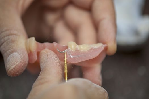 Dental technician work on denture prothesis in dental laboratory, close up