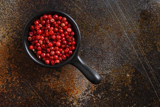 Close-up image of pepper rose, pink peppercorns on black wood background, view above space for text on side.