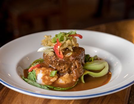 Serving of Beef Rendang curry in white bowl on restaurant table in England