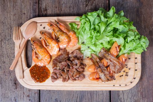 Grilled meat and shrimps with vegetables, barbecue grill food on wood background
