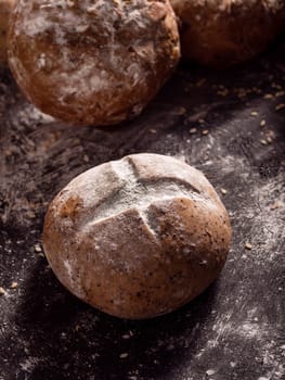 Close-up the rustic loaves of bread placed on wooden black background.