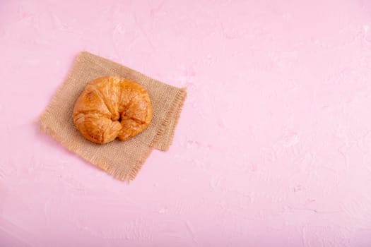 Top view croissant on the brown sack. Bread on the pink background and texture.