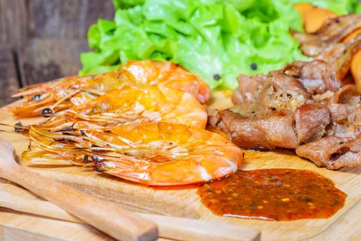 Grilled meat and shrimps with vegetables, barbecue grill food on wood background