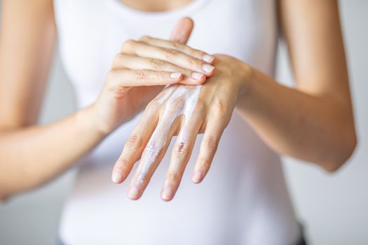 Young woman applying hand cream to care and protect skin, close up.