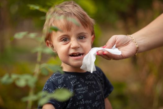 Hygiene - mom wiping the baby face skin with wet wipes. Cleaning wipe, pure, clean, outdoor