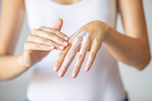 Young woman applying hand cream to care and protect skin, close up.