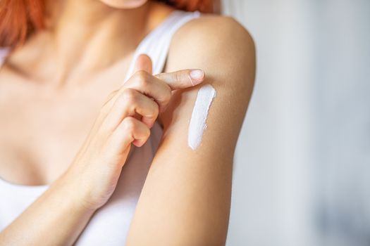 Young woman applying hand cream to care and protect skin, close up.