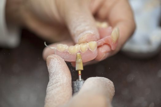 Technician make denture prothesis in dental laboratory, close up