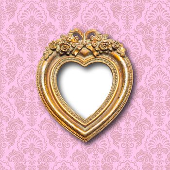 Old gold ornamental heart shape picture frame on pattern wall