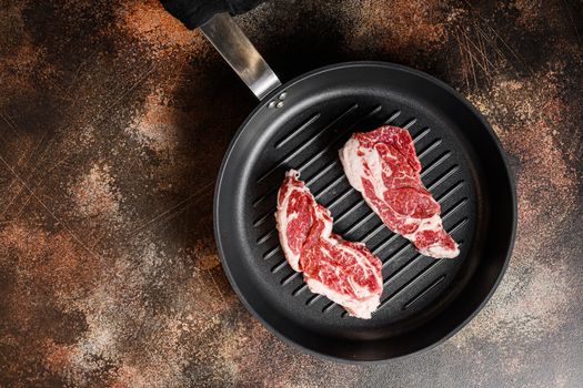 Ribeye Steak, Bone-In on the grill pan skillet or Entrecote Fillet raw top view. ove rustic metal dark background table. with space for text.