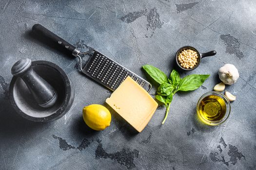 Pesto Ingredients italian recipe Fresh basil, tomatoes mortar lemon olive oil parmesan pine nuts on the stone table on gray concrete background Top view.