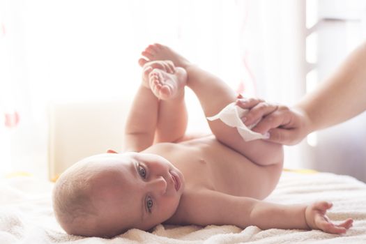 Hygiene - young mom wiping the baby skin with wet wipes carefully. Cleaning wipe, pure, clean