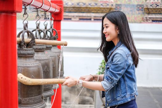 Woman ringing a bell in a Buddhist temple in Thailand