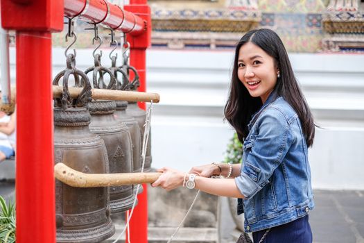 Woman ringing a bell in a Buddhist temple in Thailand