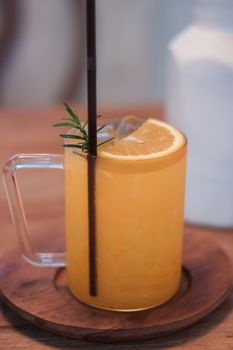 Glass of fresh orange juice with slice on wooden table