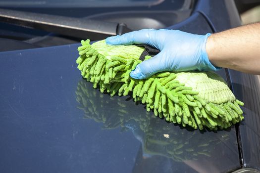 Domestic work: woman clean car in glowes with sponge in hand