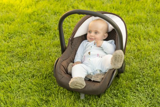 Safe Baby in car seat on grass, nature