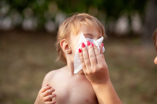 Hygiene - mom wiping the baby nose and face with wet wipes. Cleaning wipe, pure, clean, outdoor