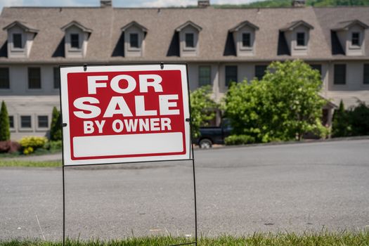Blank for sale by owner sign in front of a row of town houses or homes in the USA