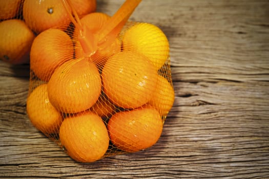 Mandarin orange in package on wood background with copy space