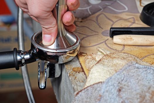 Barista compresses coffee grounds with tamper