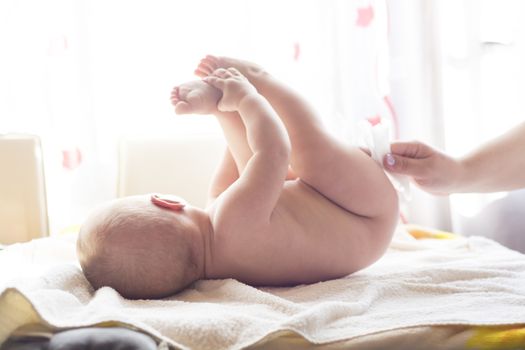 Hygiene - young mom wiping the baby skin with wet wipes carefully. Cleaning wipe, pure, clean