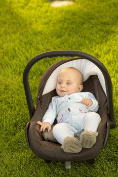 Baby in car seat on grass, nature