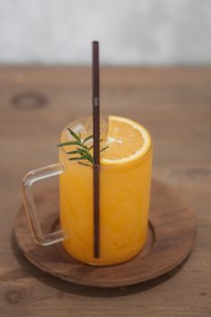 Glass of fresh orange juice with slice on wooden table