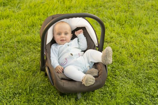 Safe baby in car seat on grass, nature