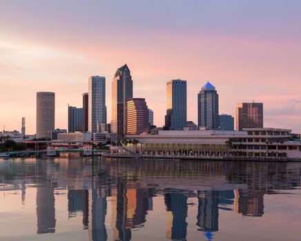 Florida skyline at Tampa with the Convention Center on the riverbank. Sun is just setting at dusk giving a fiery glow to the night sky.