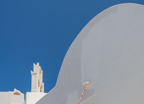 White paint being applied by roller to traditional house in Santorini