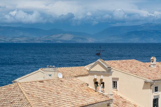 Tiled roof and bell tower of old building by Faliraki beach in Kerkyra