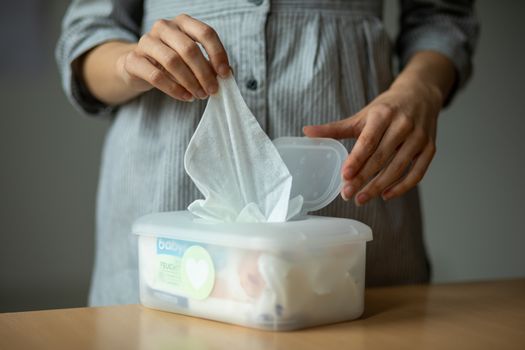 Wet wipes are universal an practical: woman hand take one wipe from big plastic box package for cleaning, home, indoor