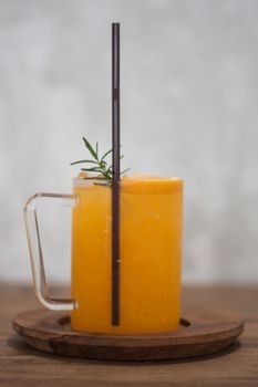 Glass of fresh orange juice with slice on wooden table