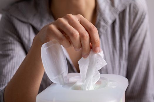 Wet wipes are universal an practical: woman hand take one wipe from big plastic box package for cleaning, home, indoor