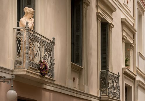 Statue on a wrought iron balcony in ancient district or neighborhood of Plaka in Athens by the Acropolis