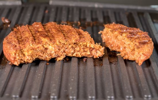 Close shot of the meat like plant-based patties for vegetarian beef burgers being grilled on hot griddle