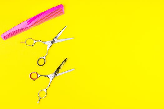 Stylish Professional Barber Scissors and comb on yellow background. Hairdresser salon concept, Hairdressing Set. Haircut accessories. Copy space image, flat lay