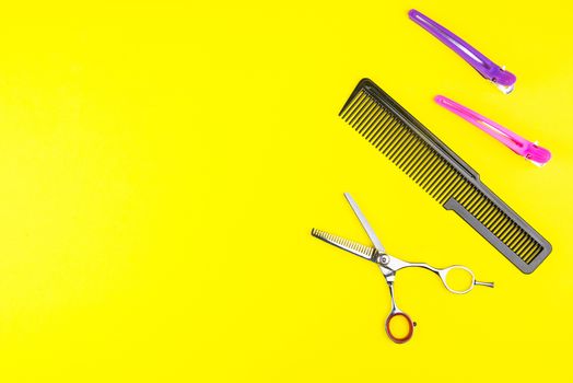 Stylish Professional Barber Scissors and comb on yellow background. Hairdresser salon concept, Hairdressing Set. Haircut accessories. Copy space image, flat lay